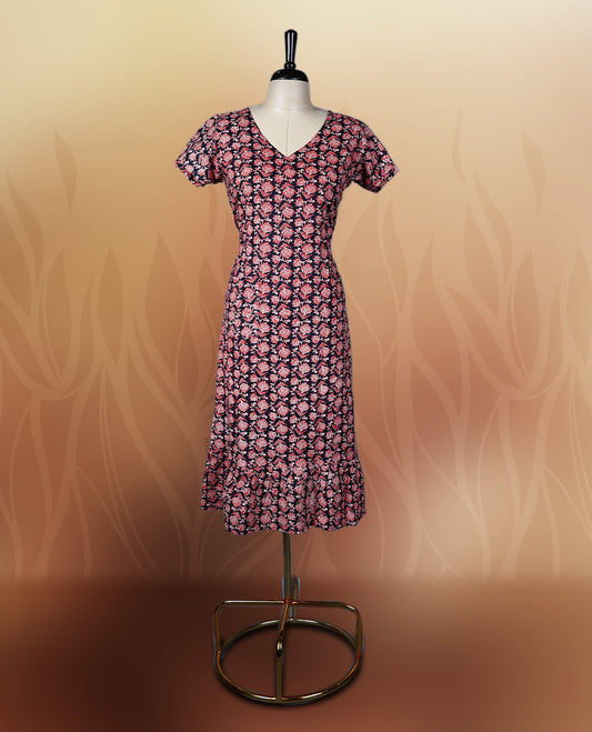 Black colour nightwear adorned with soft pink floral prints, featuring a V neckline, short sleeves, and a flared ruffle hem, A stylish and comfortable choice for daily wear, brunches, or casual outings.