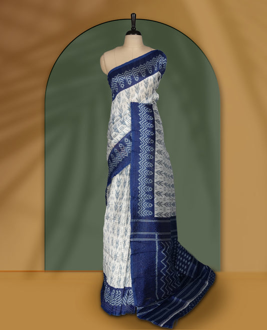 Classic off white colour saree adorned with intricate blue tribal motifs and rich woven patterns on the pallu and border & Paired with matching blouse.