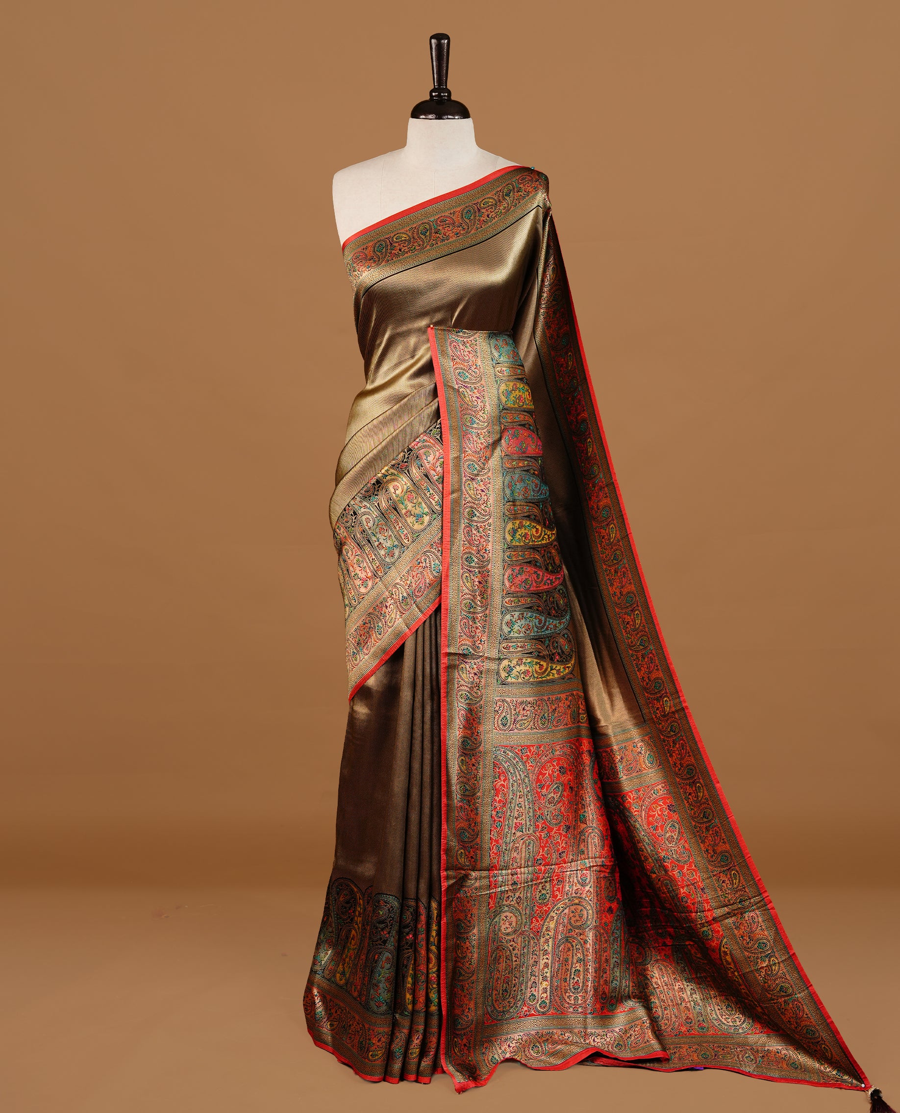 Bronze colour Pashmina Saree featuring a plain self textured body, a multicolour paisley woven border with red edging, an ornate multicolour paisley woven pallu, paired with a contrast red blouse with a matching woven border.