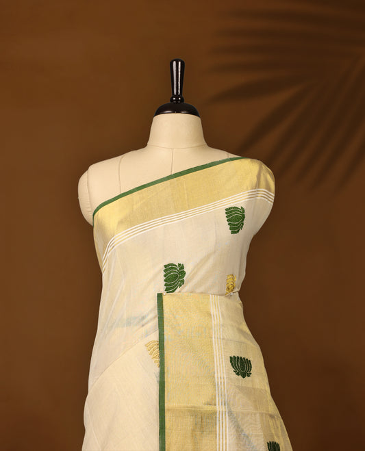 Elegant handloom soft tissue Kerala saree,Featuring a cream base with gold zari, green borders & lotus motifs, and paired with a matching blouse, perfect for festive and traditional occasions.
