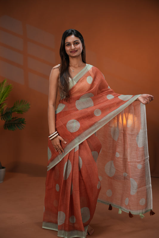 Rust Orange colour Linen saree featuring Sage Green Polka dot on body, Contrast Border and Blouse.