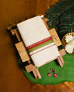 Ivory pure handloom cotton double dhoti designed with a dual tone border in red and green, accented with subtle golden zari lines, offering breathable comfort and traditional elegance for festivals, rituals, and cultural occasions.
