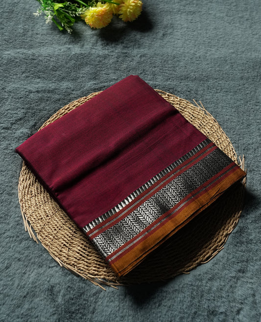 Dark Maroon colour Narayanapattu cotton saree featuring a self coloured body, yellow coloured with silver zari pattern border and pallu, pairing a matching blouse piece.