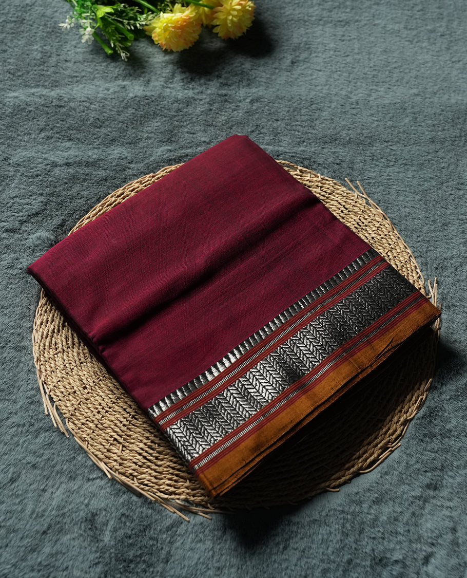 Dark Maroon colour Narayanapattu cotton saree featuring a self coloured body, yellow coloured with silver zari pattern border and pallu, pairing a matching blouse piece.