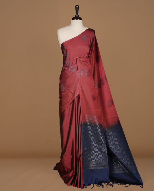 Maroon colour soft silk saree features a sleek borderless design with intricate antique zari motifs, flowing into a striking contrast blue pallu and a matching blouse piece.