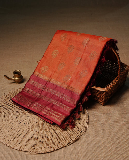 Rust orange colour pure tussar Banaras silk saree featuring elegant gold zari motifs across the body, complemented by a contrast magenta border with rich zari detailing. Comes with a matching blouse piece