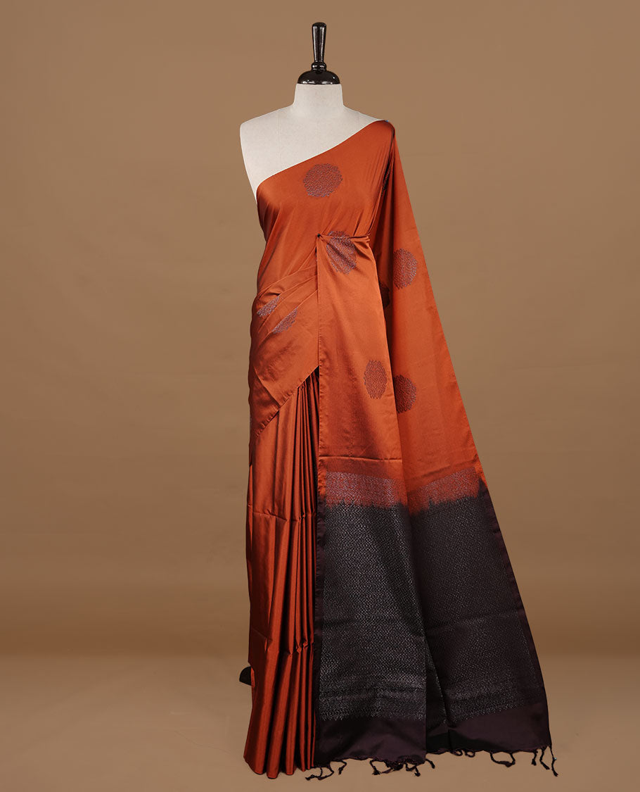 Rust orange colour soft silk saree features a sleek borderless design with intricate antique zari motifs, flowing into a striking contrast Black berry pallu and a matching blouse piece.