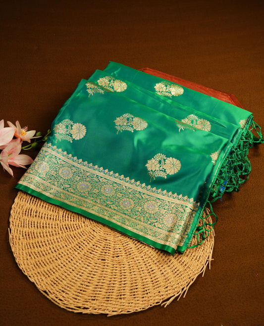 Emerald green colour Banaras Satin Crepe saree featuring gold zari floral motifs on the body, a richly woven traditional border with intricate gold zari detailing, and paired with a matching blouse.