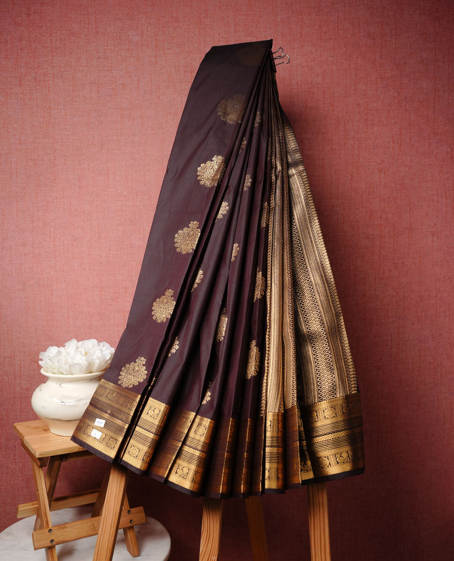 Dark chocolate colour soft silk saree featuring Gold zari motifs on body, complemented by self colour with traditional border, paired with matching blouse piece.