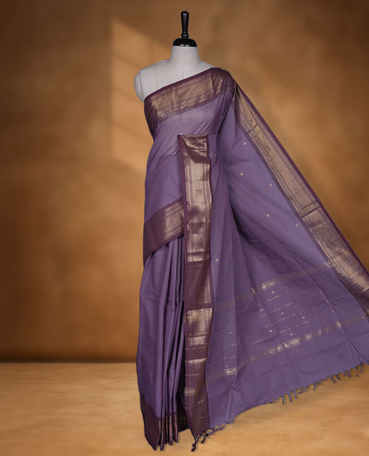 Dark lavender colour chettinad cotton saree featuring small gold zari buttas on body highlighting contrast magenta purple colour with gold zari traditional border, pallu and paired with matching blouse piece.
