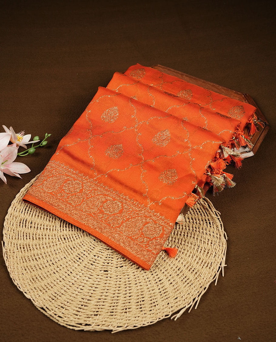 Orange semi Banaras saree with gold zari buta motifs, finished with a traditional gold zari border and pallu, paired with a matching blouse.