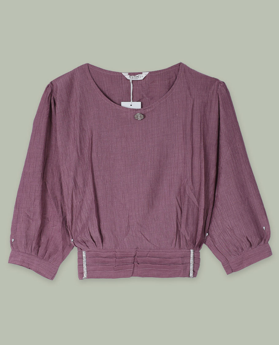 Dusty mauve three-quarter sleeve top with round neckline, metal button detail at the neck, and a pleated waistband accented with slim metallic trims.