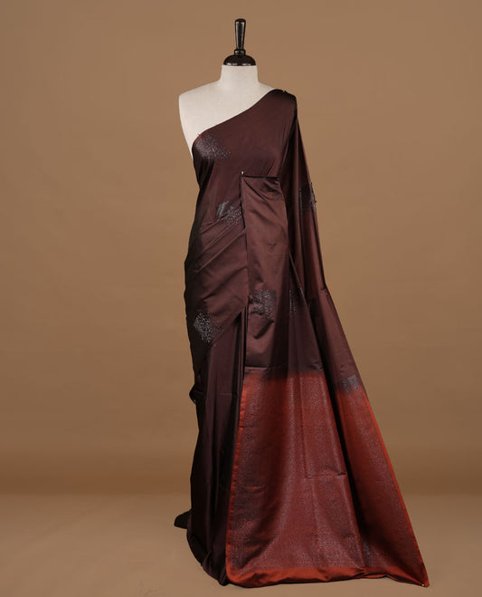 Chocolate colour soft silk saree features a sleek borderless design with intricate antique zari motifs, flowing into a striking contrast burnt orange and a matching blouse piece.