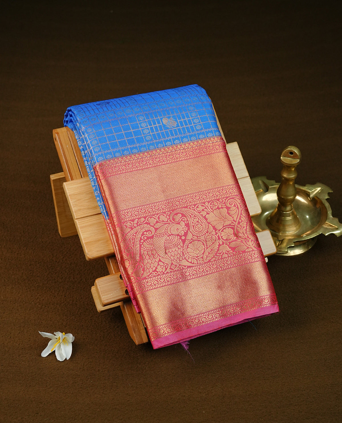 Blue colour semi wedding saree featuring gold zari check with peacocok motifs on body complemented by contrast magenta colour with traditional border, comes with matching blouse piece.