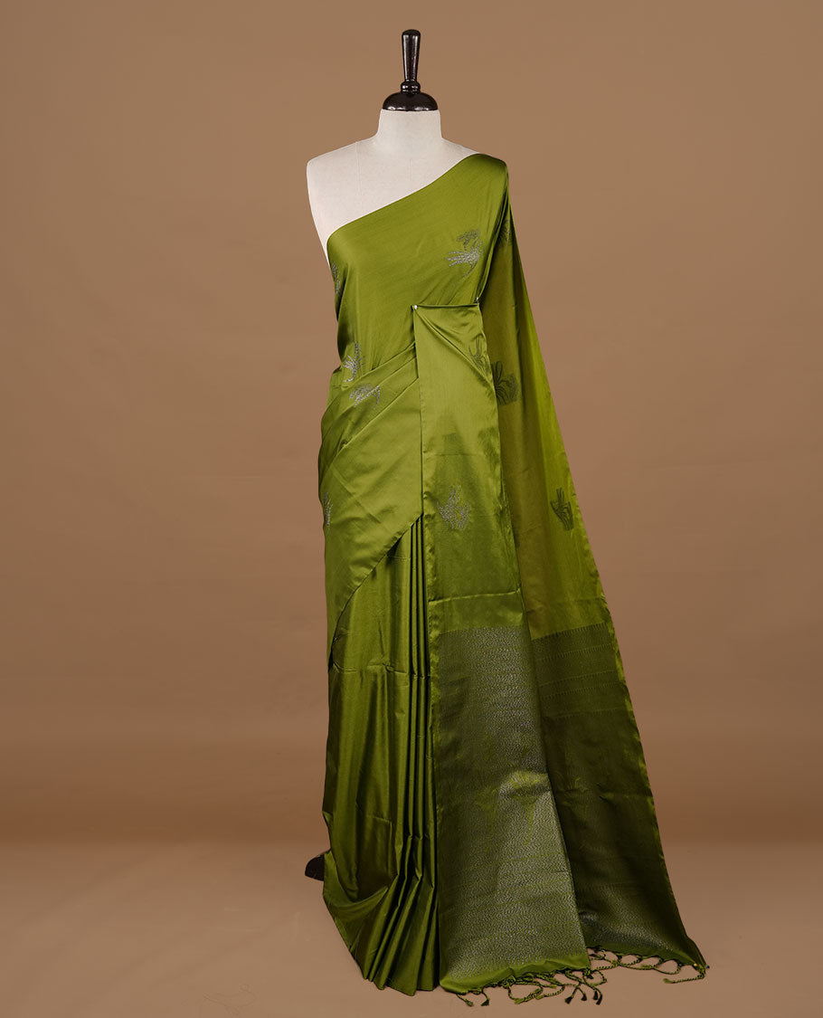 Olive soft silk saree features a sleek borderless design with intricate antique zari motifs, flowing into a seamless self colored pallu and a matching blouse piece.