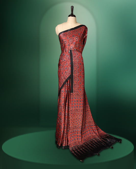 Red colour semi modal saree adorned with intricate all over traditional motifs in black and gold, enhanced by a rich patterned pallu and black border, paired with a matching blouse