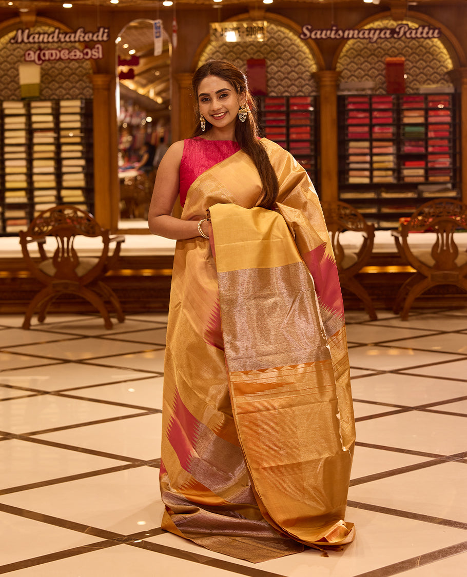 Elegant golden beige colour Kancheepuram silk saree featuring subtle woven geometric highlights with soft pink accents, beautifully paired with a rich contrast pallu and styled with a vibrant blouse