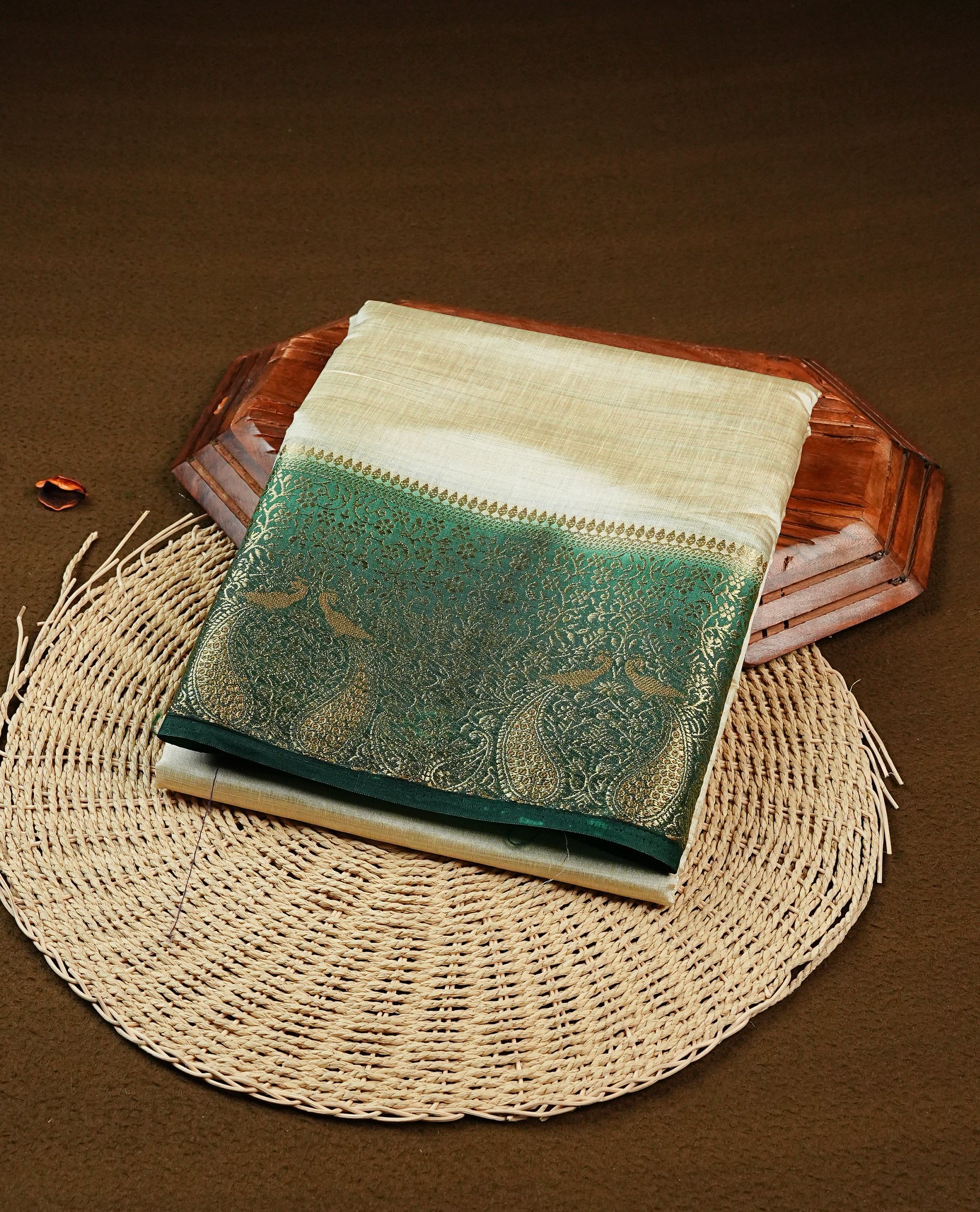 Light gold tussar saree featuring Elegant plain body, complemented by contrast Bottle green colour with Gold zari Floral kodi with Peacock Pattern border, comes with matching blouse piece.