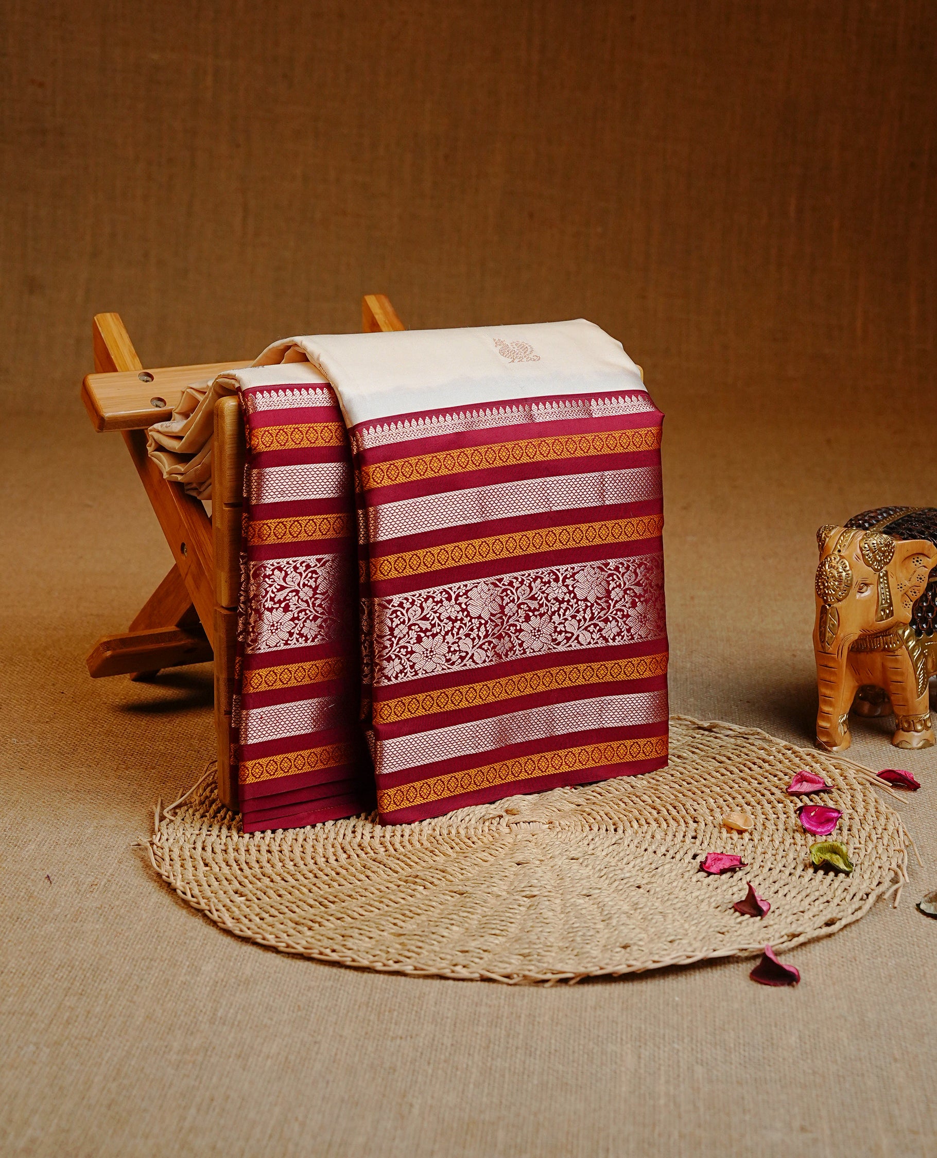Cream colour kancheepuram silk saree featuring Gold zari peacock Motifs on body, highlight Maroon colour with gold zari & mustard stripe pattern border, paired with a matching blouse piece.
