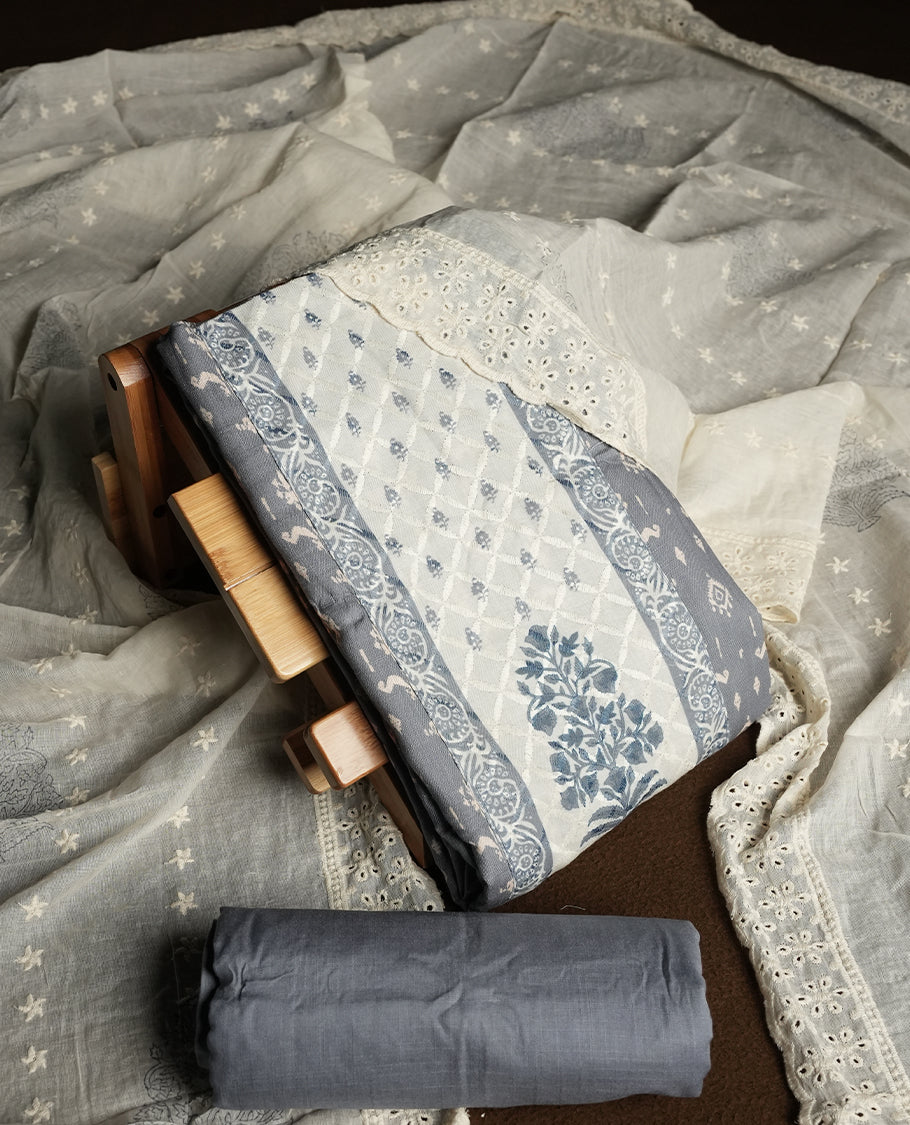 Grey and off white colour churidar material featuring elegant thread work on the neckline and floral motifs on the body, dupatta is adorned with delicate embroidered motifs and scalloped lace border & Comes with a matching bottom.