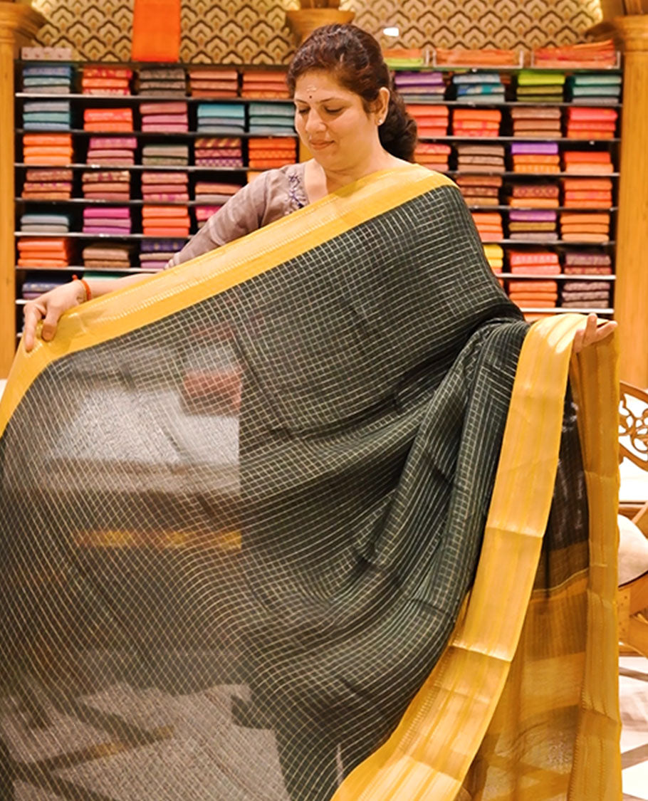 Bottle green colour moss chiffon saree featuring gold zari checks designed body, complemented by contrast Yellow colour zari jacquard border, paired with contrast colour blouse piece.