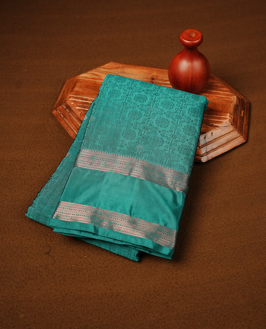 Teal Green Colour  Semi Soft Slik  Saree Featuring An Elegant Self Floral Woven Body, Enhanced By A Traditional Rose Gold Zari Border And Rich Pallu, Paired With A Matching Blouse Piece.