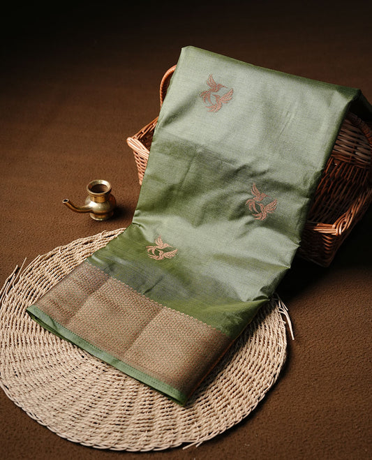Olive colour semi banaras tussar silk saree highlighting gold zari bird motifs on body, complemented by self colour with antique zari border, paired with matching blouse piece.