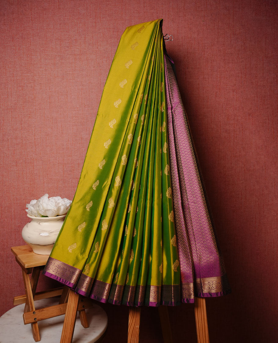 Lemon green colour soft silk saree featuring Gold zari motifs on body, complemented by contrast purple colour with traditional border, paired with matching blouse piece.