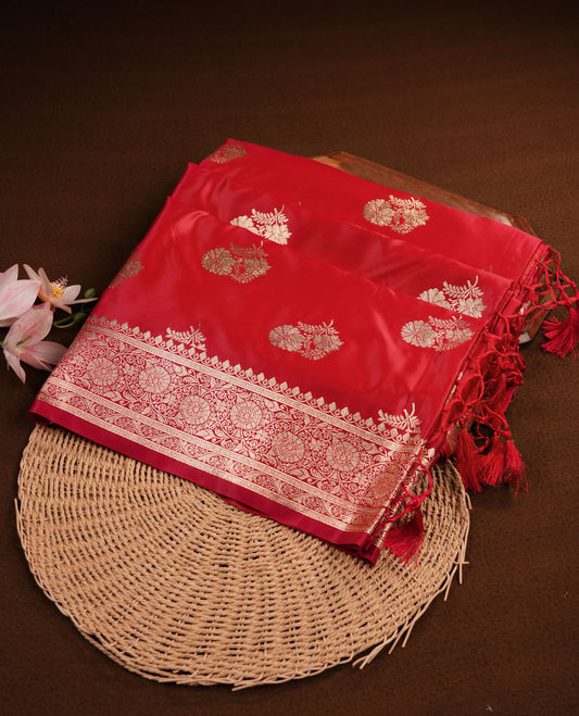 Bright red colour Banaras Satin Crepe saree featuring gold zari floral motifs on the body, a richly woven traditional border with intricate gold zari detailing, and paired with a matching blouse.