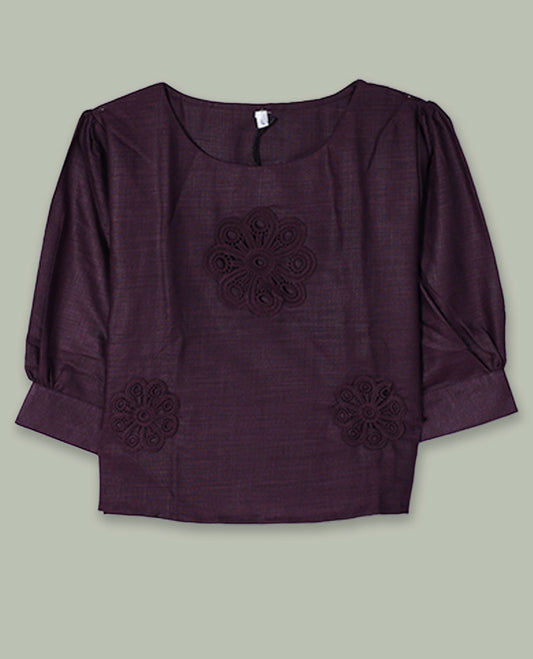 Deep plum three-quarter sleeve top with round neckline and tonal crochet floral appliqués placed at the center front and near the hem