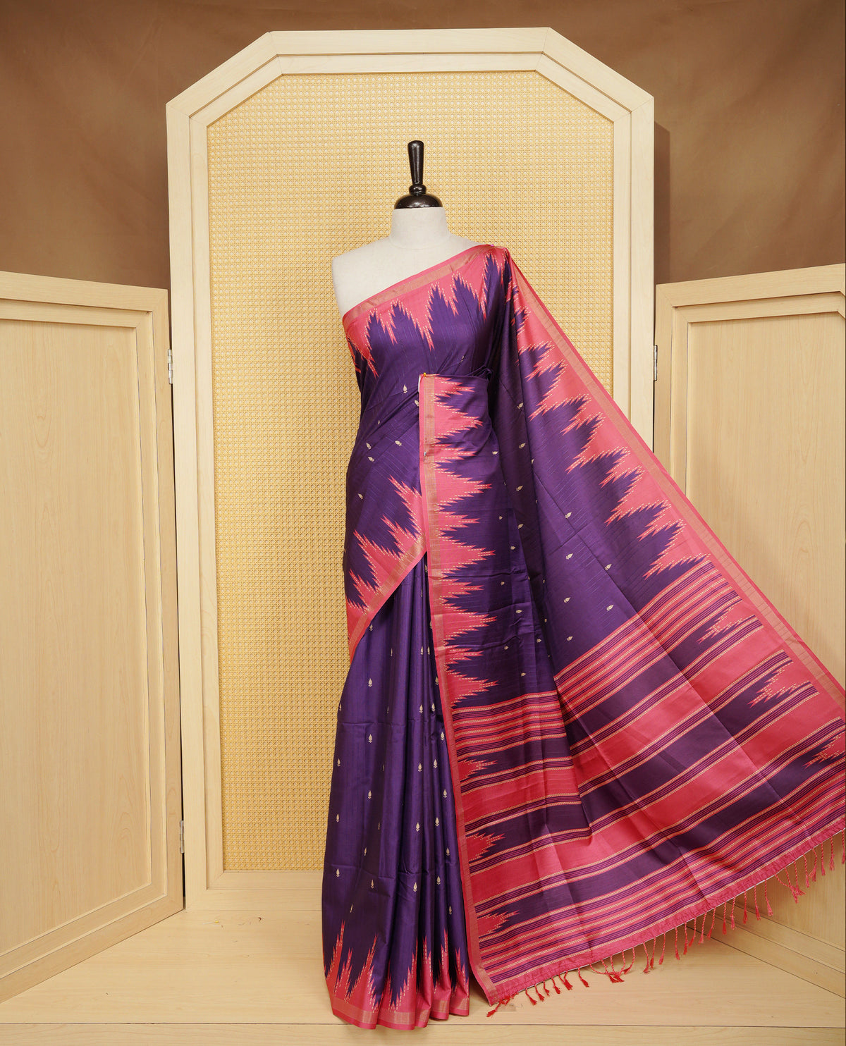 Violet And Peach Colour Kattan silk saree featuring buttas all over the body, a temple-designed border &  a contrasting striped pallu with tassels. Paired with a matching contrast-striped blouse piece.