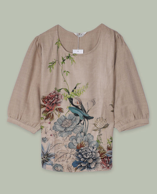 Beige round-neck top with elbow-length sleeves and placement floral print in muted blue, green, and rose tones along the front hem and side.