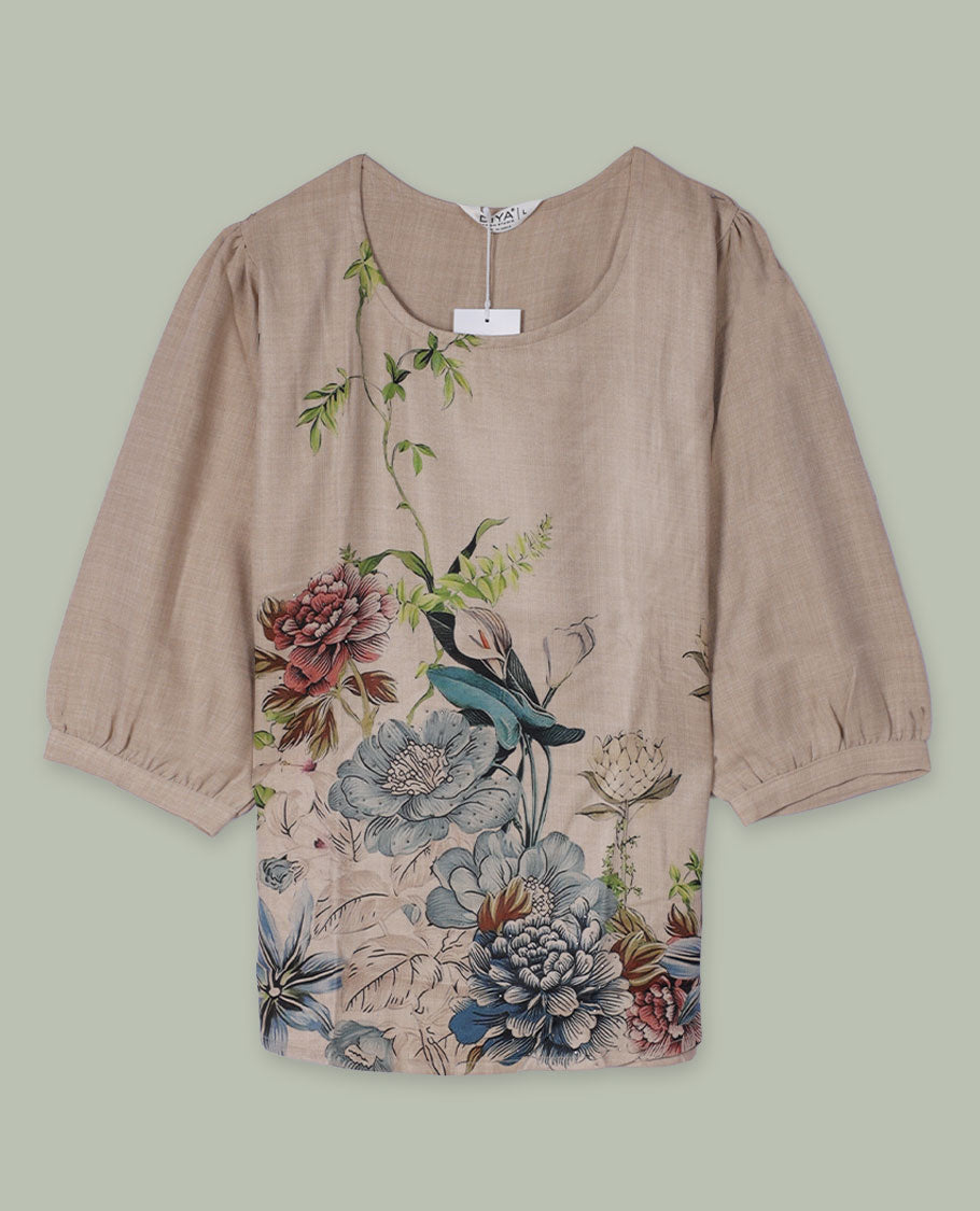 Beige round-neck top with elbow-length sleeves and placement floral print in muted blue, green, and rose tones along the front hem and side.