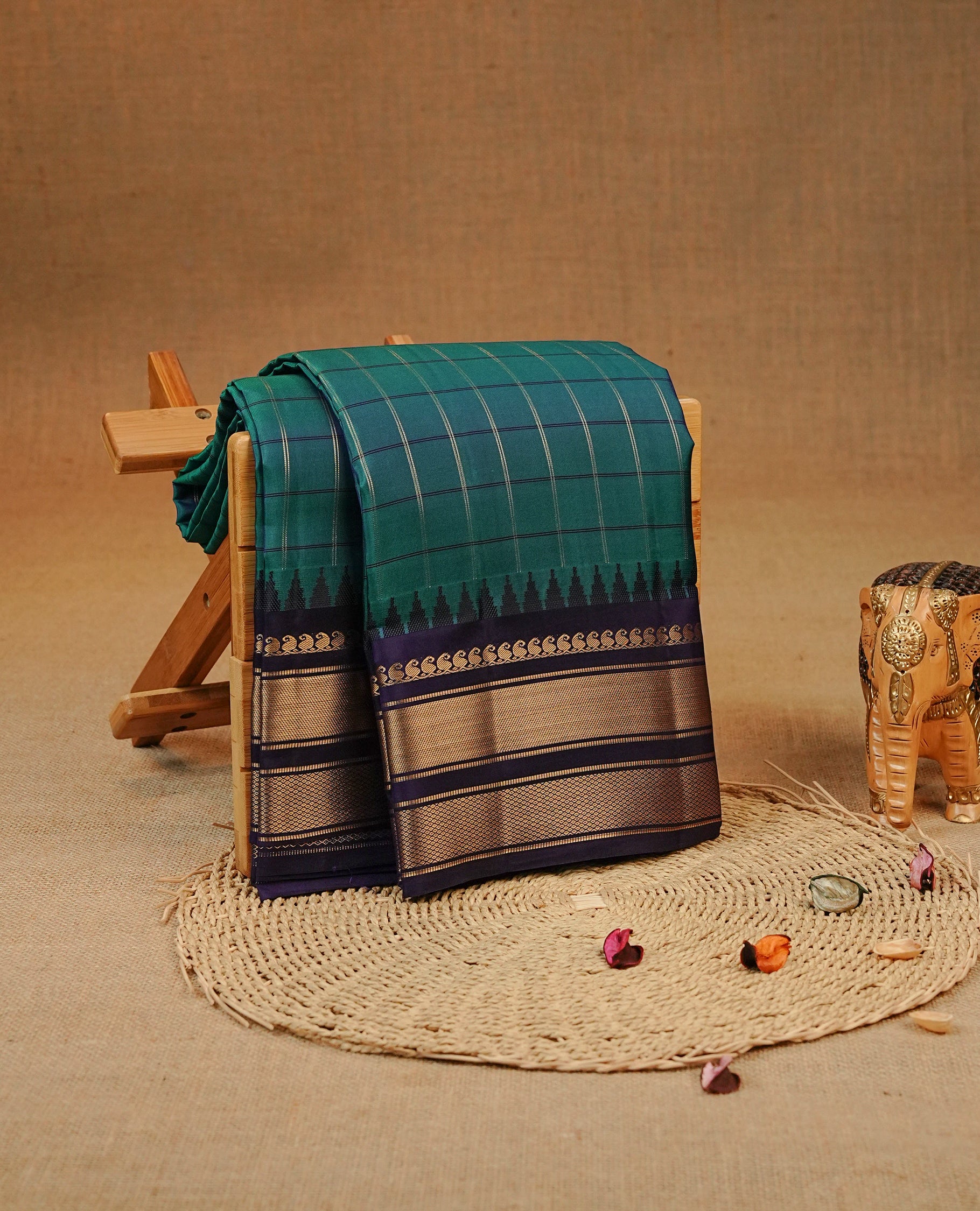 Peacock Blue colour Kancheepuram silk saree featuring  Check pattern on body, complemented by Navy blue colour with Traditional border, comes with matching blouse piece.