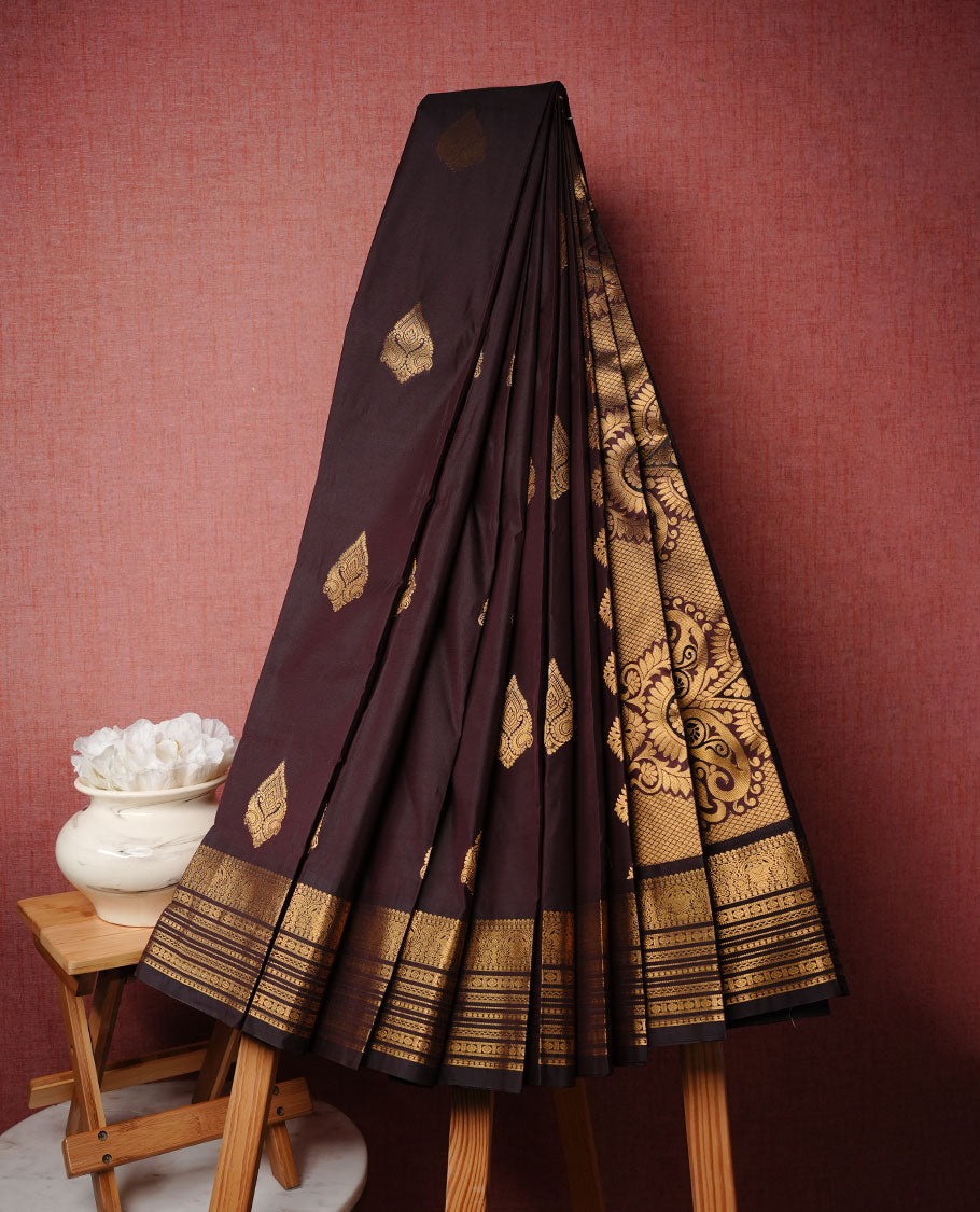 Chocolate colour soft silk saree featuring Gold zari motifs on body, complemented by self colour with traditional border, paired with matching blouse piece.