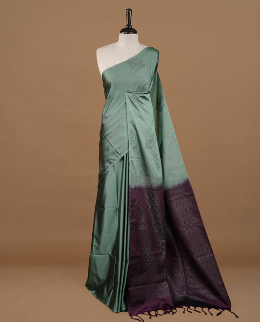 Pastel green colour soft silk saree features a sleek borderless design with intricate antique zari motifs, flowing into a striking contrast purple pallu and a matching blouse piece.