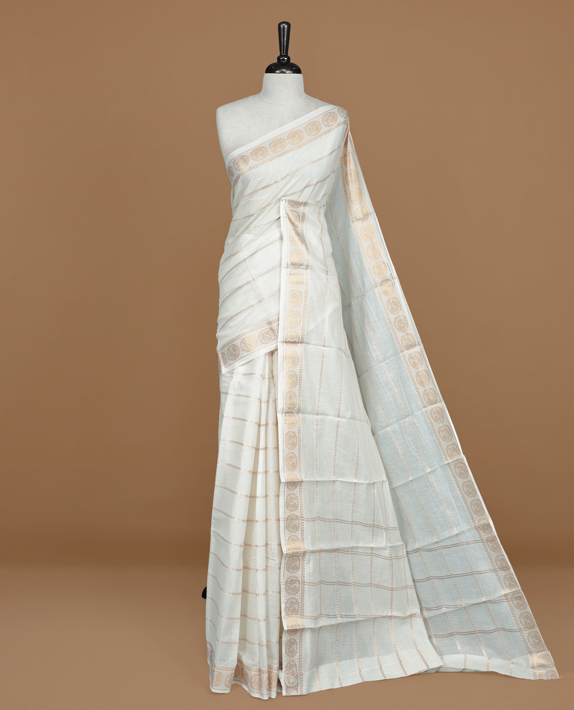 Off white colour Sungudi cotton saree featuring Gold zari Zigzag stripes on body, Gold zari Peacock chakram design on Self colour border, paired with matching blouse piece.