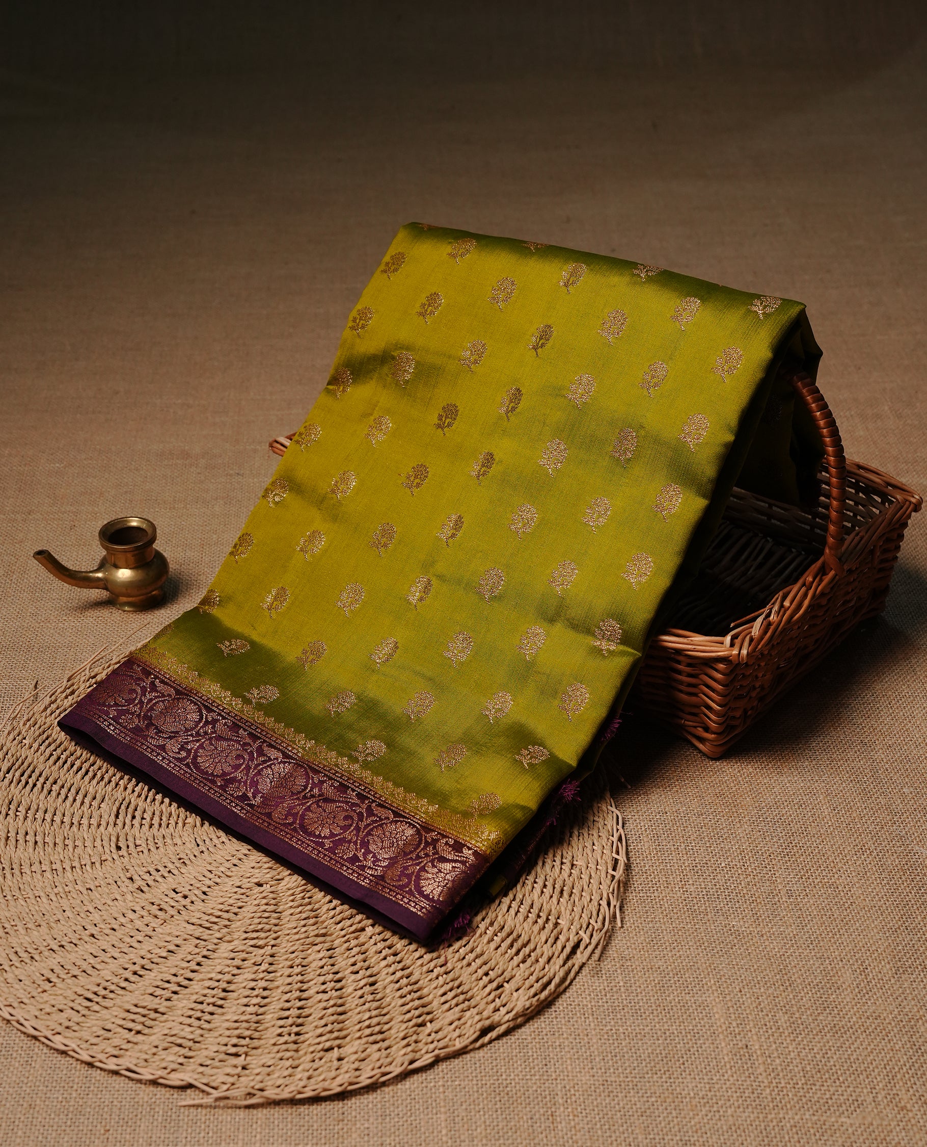 Olive colour Banaras tussar silk saree featuring elegant gold zari buttas across the body, complemented by a contrast Maroon border with rich zari detailing. Comes paired with a matching blouse piece.