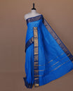 Sky blue colour sungudi cotton saree featuring gold zari check pattern across body, contrast Dark blue colour with gold zari peacock and floral pattern on border, without blouse piece.