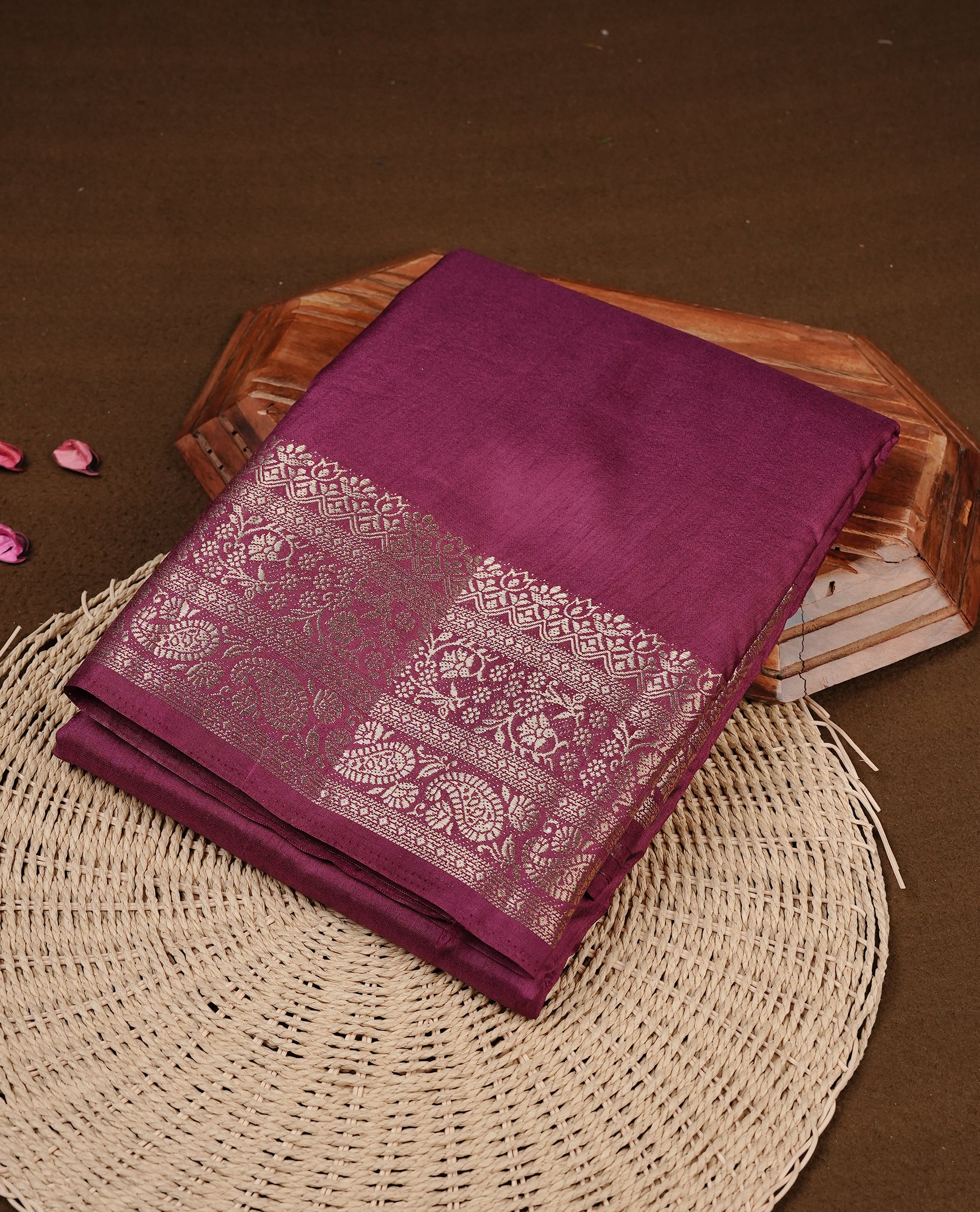 Burgundy colour semi Tussar silk saree featuring an elegant plain body, complemented by a self colour border adorned with traditional gold zari floral kodi patterns. Comes paired with a matching blouse piece.