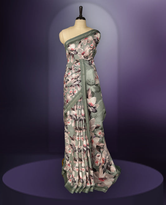 Pastel green saree adorned with elegant floral prints on the body, enhanced with a subtle matching border, complemented by a beautifully printed pallu featuring blooming flowers, and paired with a matching blouse.
