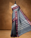 Grey colour sungudi cotton saree featuring gold zari check pattern across body, contrast Purple colour with gold zari peacock pattern on border, without blouse piece.