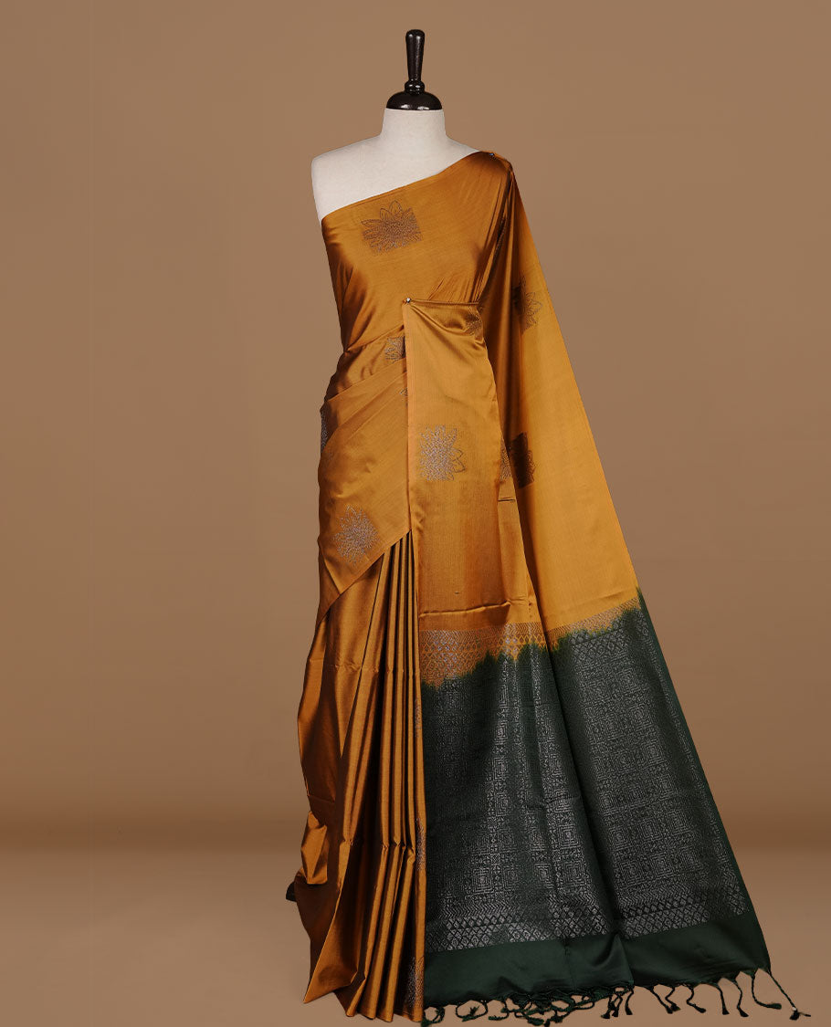 Mustard colour soft silk saree features a sleek borderless design with intricate antique zari motifs, flowing into a striking contrast dark green pallu and a matching blouse piece.