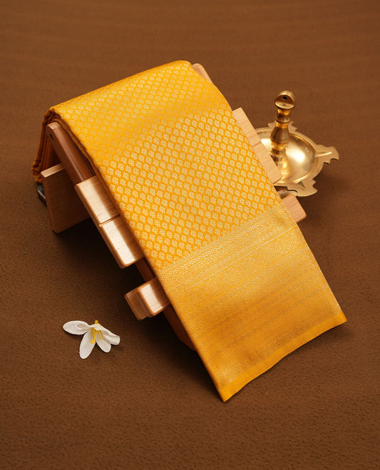 Light mustard colour semi silk brocade saree featuring intricate Gold patterns across the body, complemented by a Self colour woven border and pallu, paired with a matching blouse.