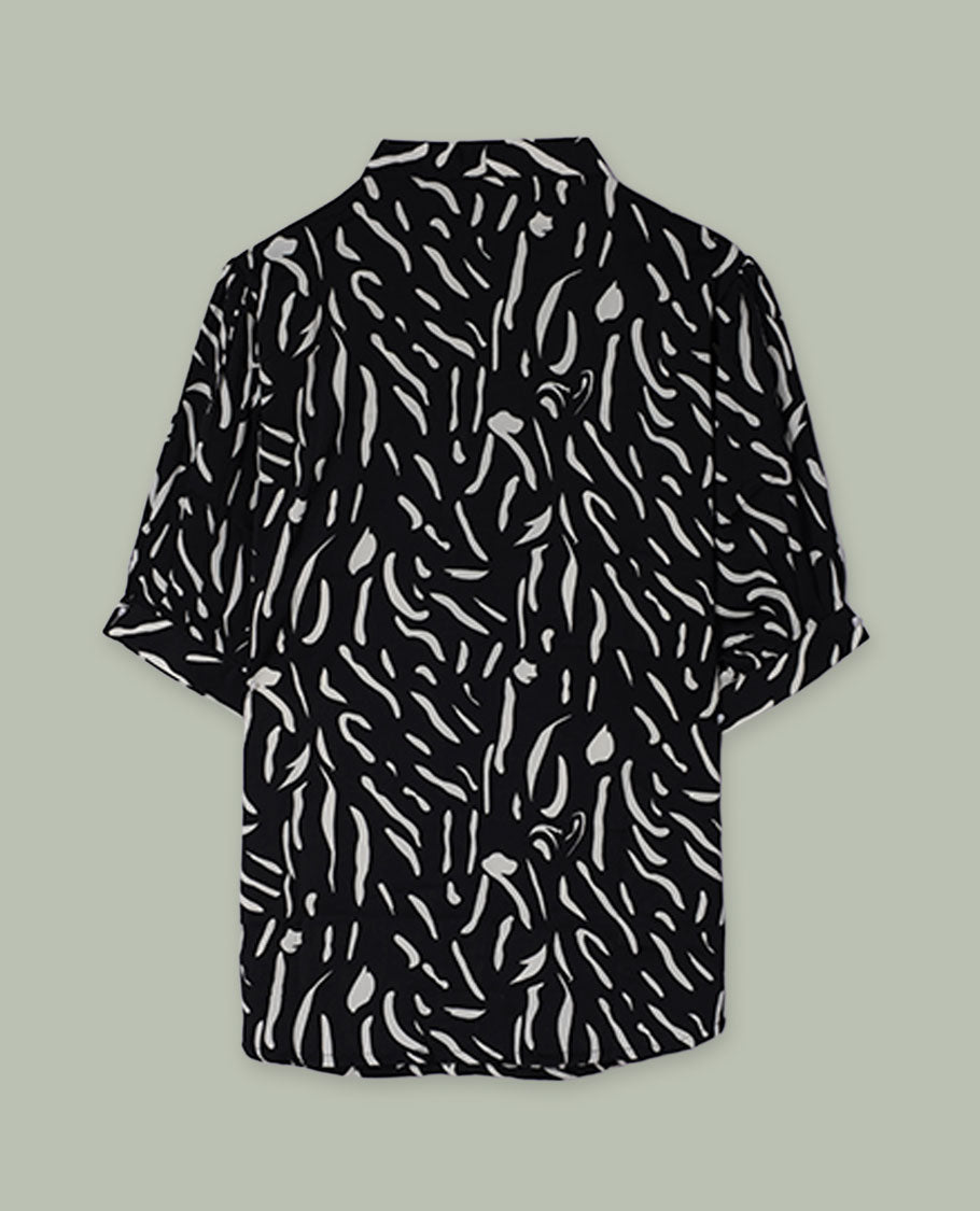Black short-sleeve shirt top with collared neckline and all-over white abstract dash print, shown from the back.