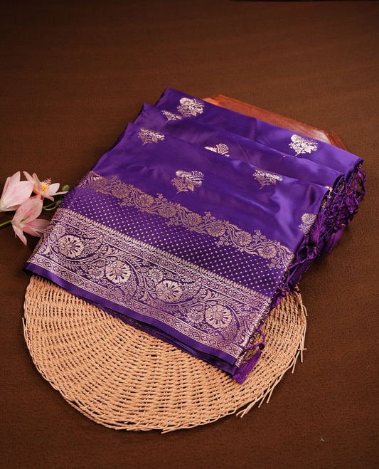 Indigo colour Banaras Satin Crepe saree featuring gold zari floral motifs on the body, a richly woven traditional border with intricate gold zari detailing, and paired with a matching blouse.