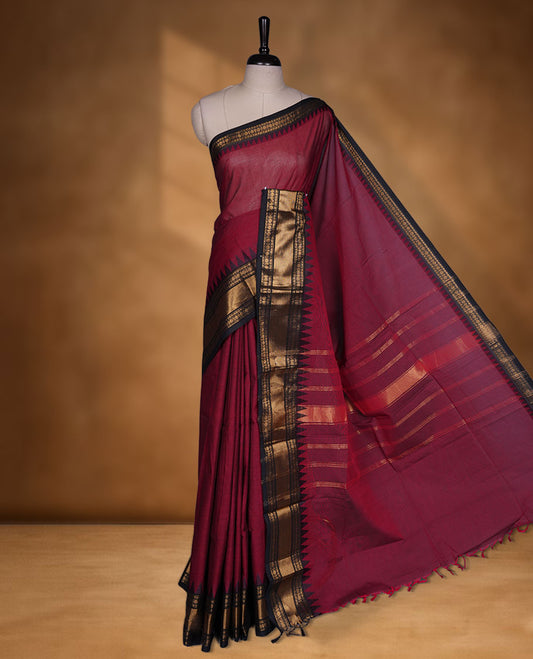 Deep red colour chettinad cotton saree featuring elegant plain body highlighting contrast black colour with gold zari traditional border, pallu and paired with matching blouse piece.