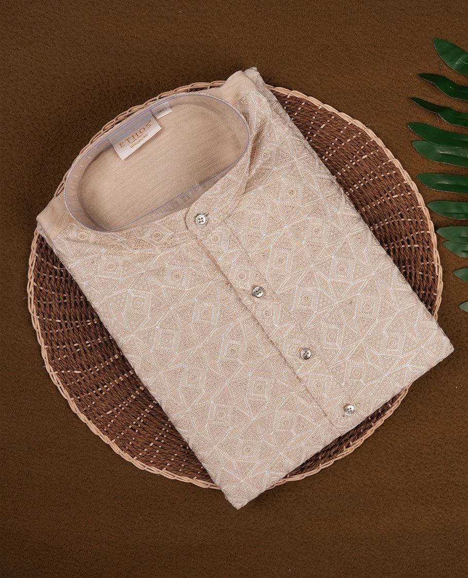 Beige colour semi silk kurta set with all over woven geometric motifs, mandarin collar with subtle embroidered detailing on the placket, and paired with a matching bottom.