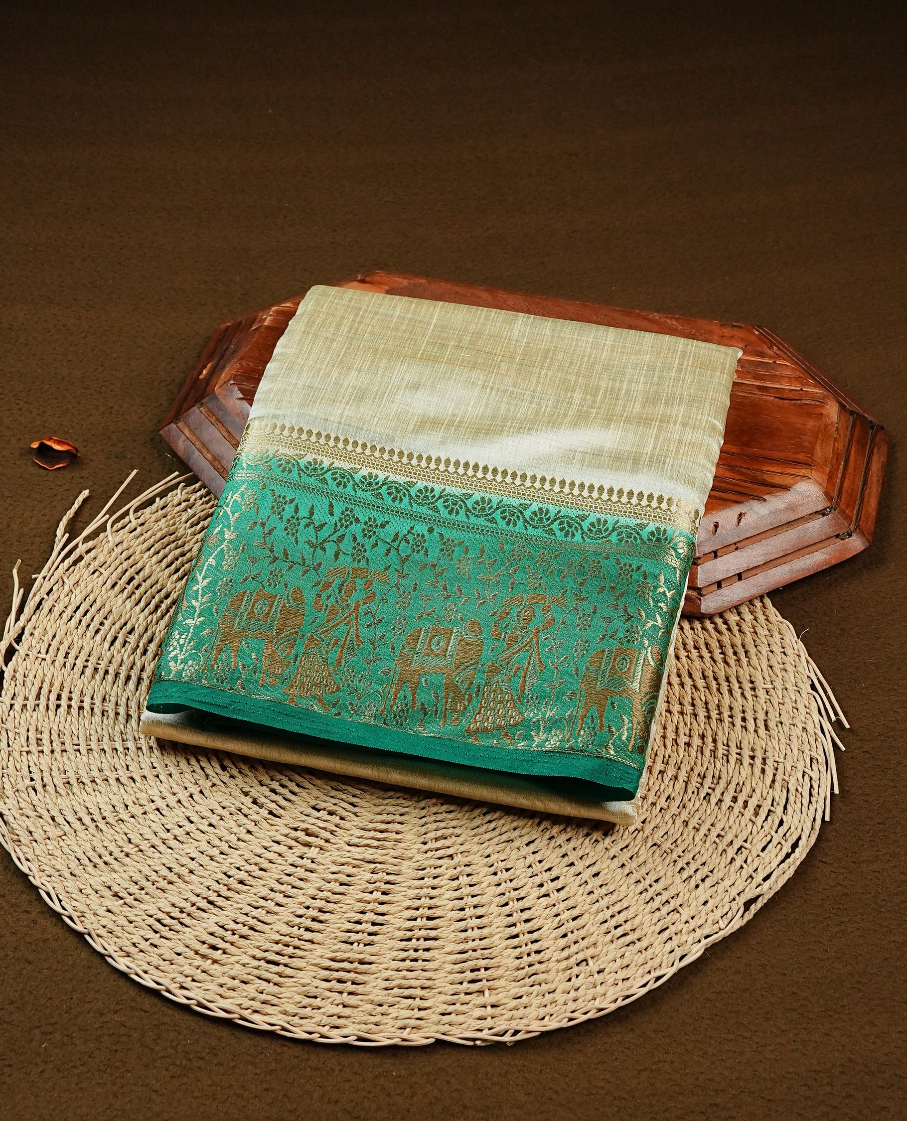 Light gold tussar saree featuring Elegant plain body, complemented by contrast green colour with Gold zari Floral kodi with Elephant Pattern border, comes with matching blouse piece.