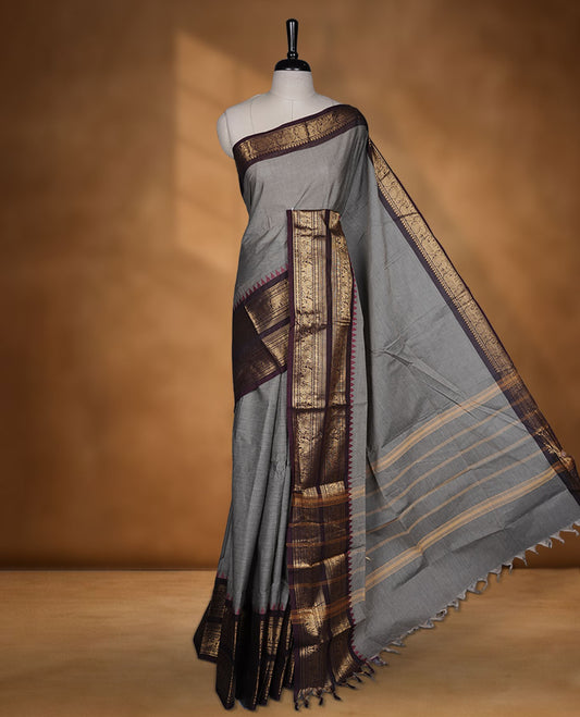 Grey colour chettinad cotton saree featuring plain body, paired with a black colour traditional gold zari border paired with matching blouse.